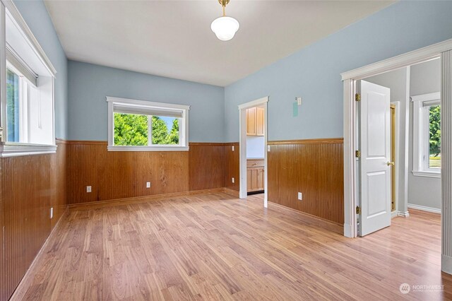 empty room with light hardwood / wood-style flooring and wooden walls