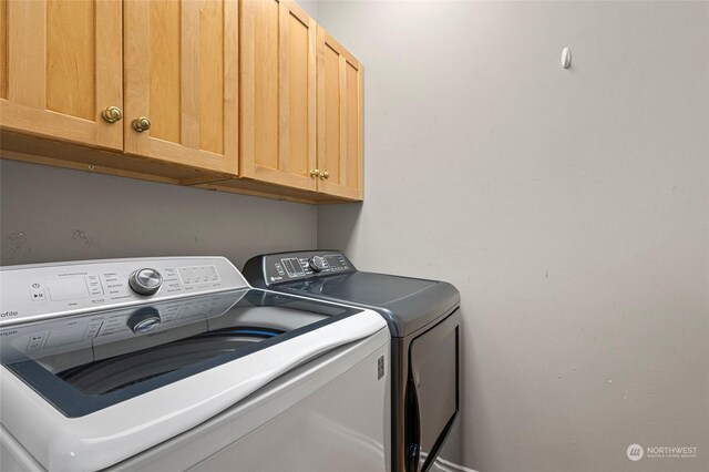 laundry room featuring separate washer and dryer and cabinets