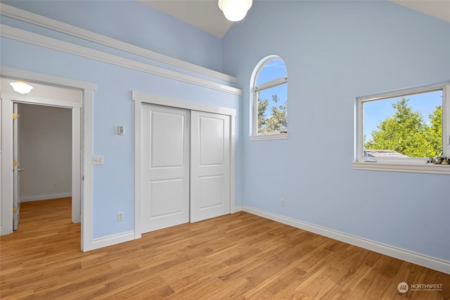 unfurnished bedroom featuring a high ceiling, a closet, and light hardwood / wood-style floors