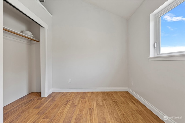 unfurnished bedroom with multiple windows, light wood-type flooring, and a closet