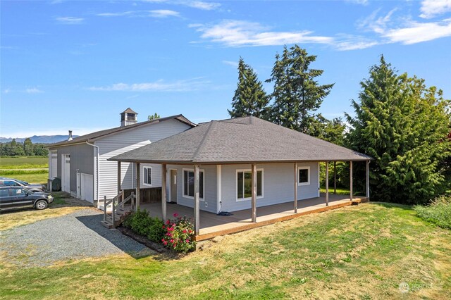 rear view of house with a porch, a garage, and a lawn