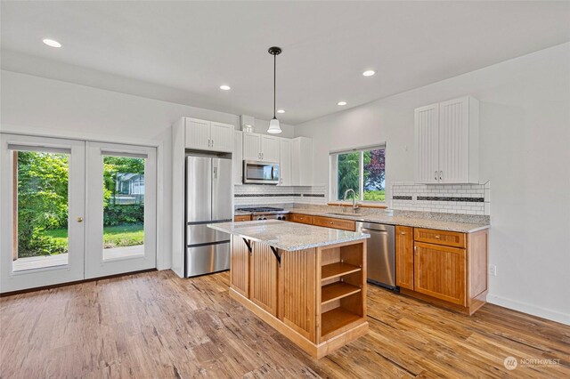 kitchen featuring stainless steel appliances, white cabinets, plenty of natural light, a center island, and backsplash