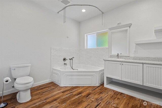 bathroom featuring vanity, wood-type flooring, toilet, and a tub