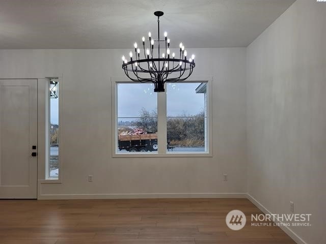 unfurnished dining area with hardwood / wood-style flooring and a notable chandelier