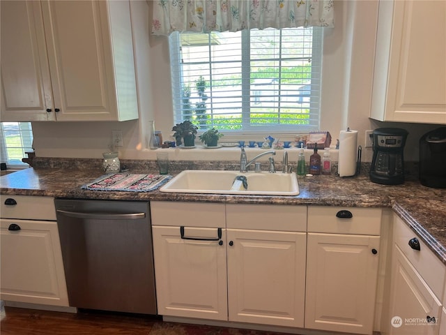 kitchen with white cabinetry, sink, stainless steel dishwasher, and dark stone countertops