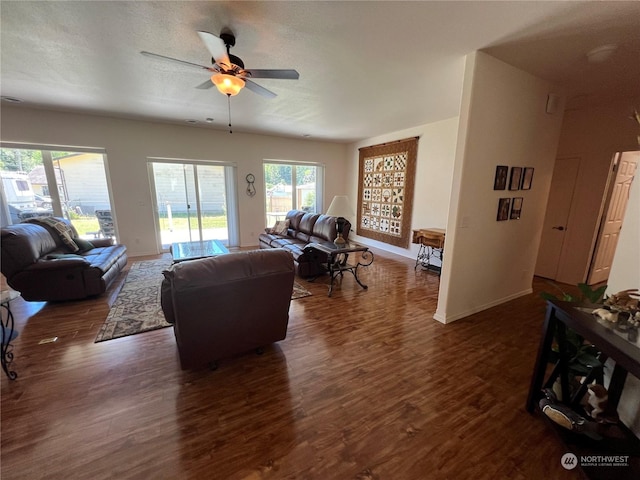 living room with dark hardwood / wood-style flooring, a textured ceiling, and ceiling fan