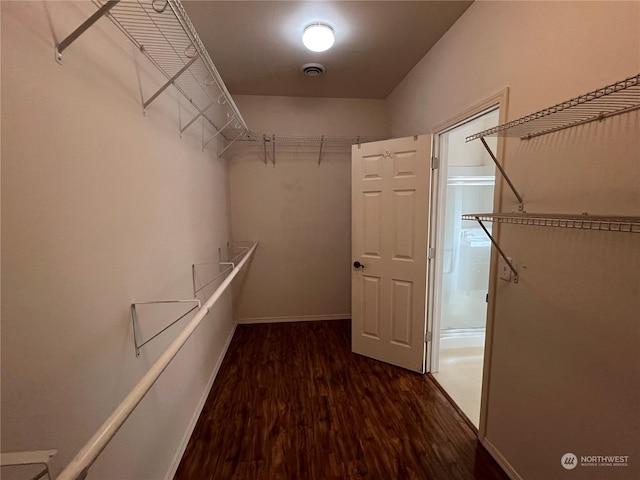 walk in closet with dark wood-type flooring