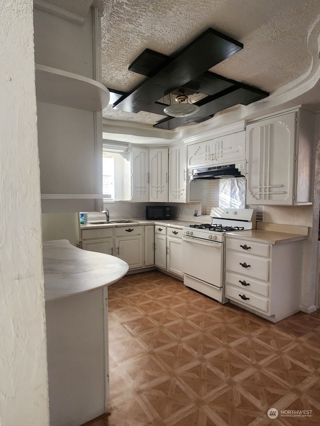 kitchen with white range with gas cooktop, sink, white cabinets, and a textured ceiling