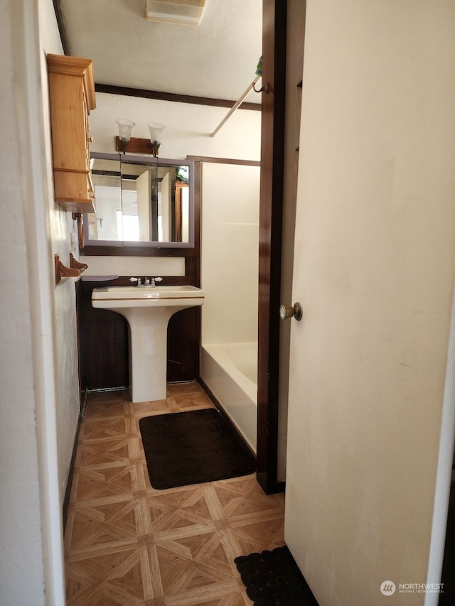 bathroom featuring plus walk in shower, parquet flooring, and sink