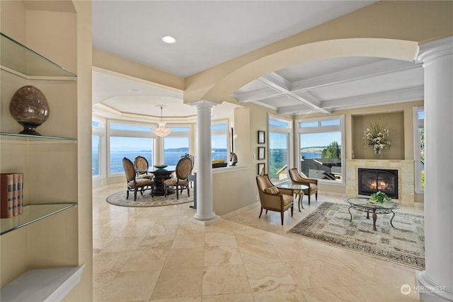 sitting room featuring beam ceiling, decorative columns, a water view, coffered ceiling, and a high end fireplace