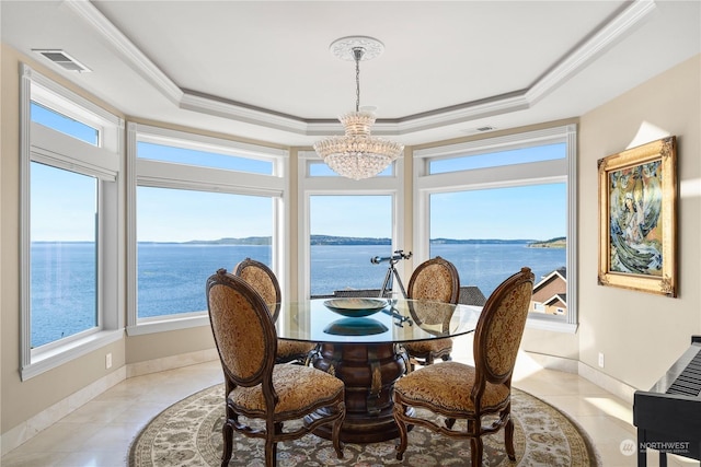 tiled dining space featuring a water view, plenty of natural light, and a tray ceiling