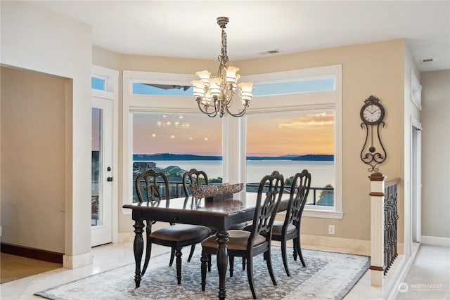 dining space with a notable chandelier and a water view