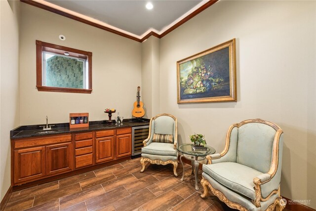 sitting room with ornamental molding, indoor wet bar, and beverage cooler