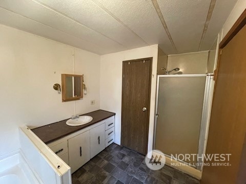 bathroom featuring an enclosed shower, vanity, and a textured ceiling