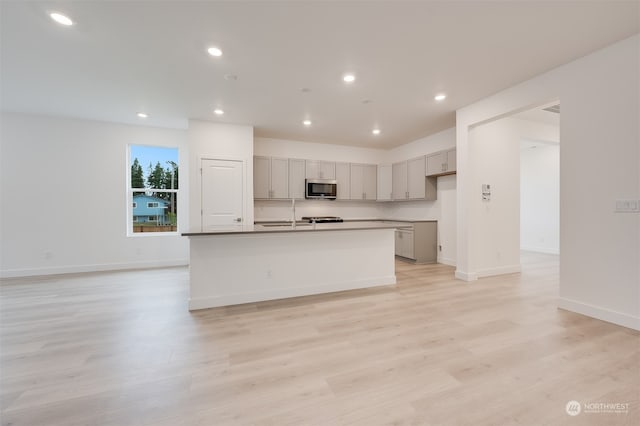29209 217th Pl SE Unit 30, Black Diamond, WA 98010 - kitchen with stainless steel microwave, a kitchen island with sink, light wood-type flooring, and gray cabinets