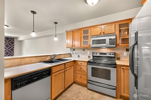 kitchen with pendant lighting, sink, decorative backsplash, and appliances with stainless steel finishes