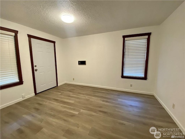 spare room featuring a textured ceiling and dark hardwood / wood-style flooring