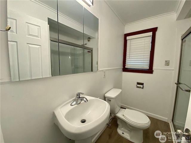 bathroom with sink, crown molding, hardwood / wood-style floors, a shower with shower door, and toilet