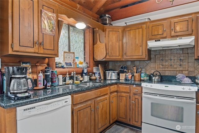 kitchen with dark stone counters, white appliances, sink, decorative backsplash, and wood-type flooring