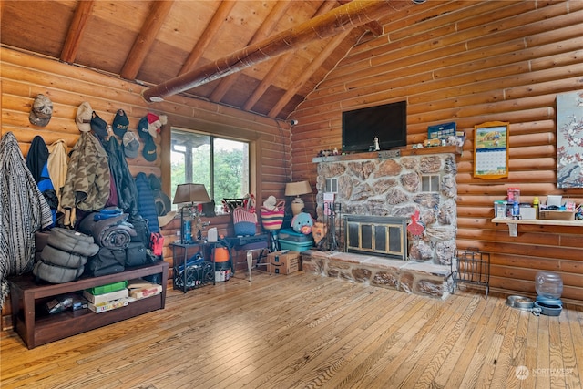 living room featuring beam ceiling, light hardwood / wood-style flooring, wooden ceiling, a stone fireplace, and high vaulted ceiling