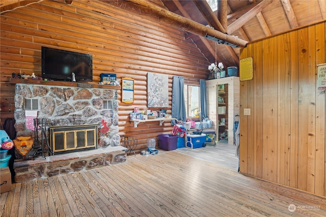 living room with log walls, beamed ceiling, a stone fireplace, light wood-type flooring, and wooden ceiling