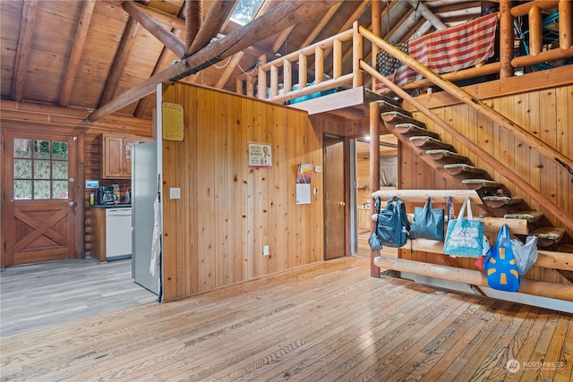 unfurnished living room with light hardwood / wood-style floors, wooden ceiling, wood walls, and vaulted ceiling with beams