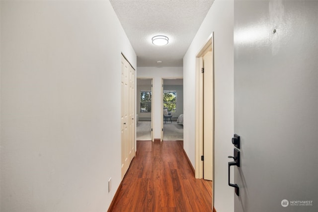 hall with dark hardwood / wood-style flooring and a textured ceiling