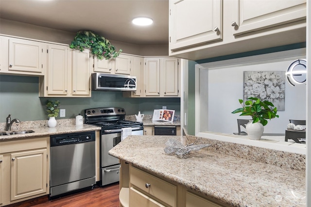 kitchen featuring sink, dark wood-type flooring, stainless steel appliances, and light stone countertops