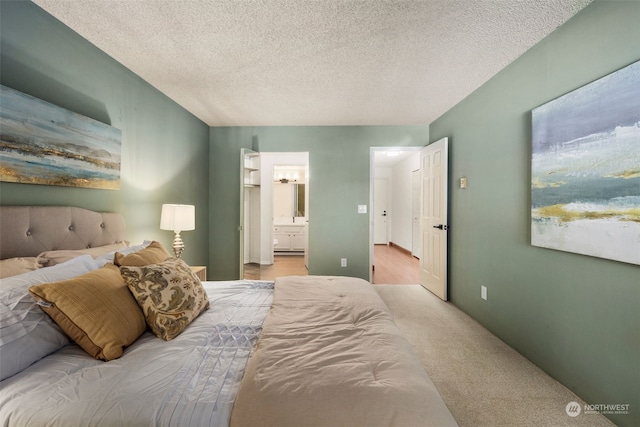 carpeted bedroom with ensuite bath and a textured ceiling