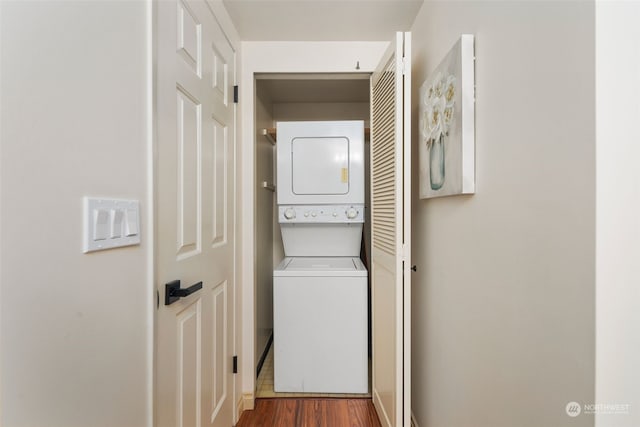 clothes washing area featuring stacked washing maching and dryer and dark wood-type flooring