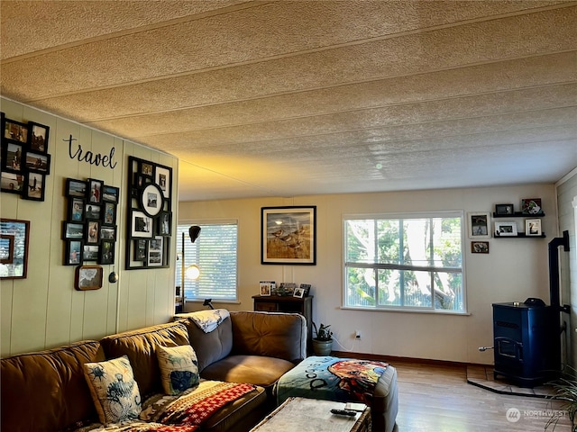 living room featuring wood walls, a wood stove, hardwood / wood-style flooring, and a textured ceiling