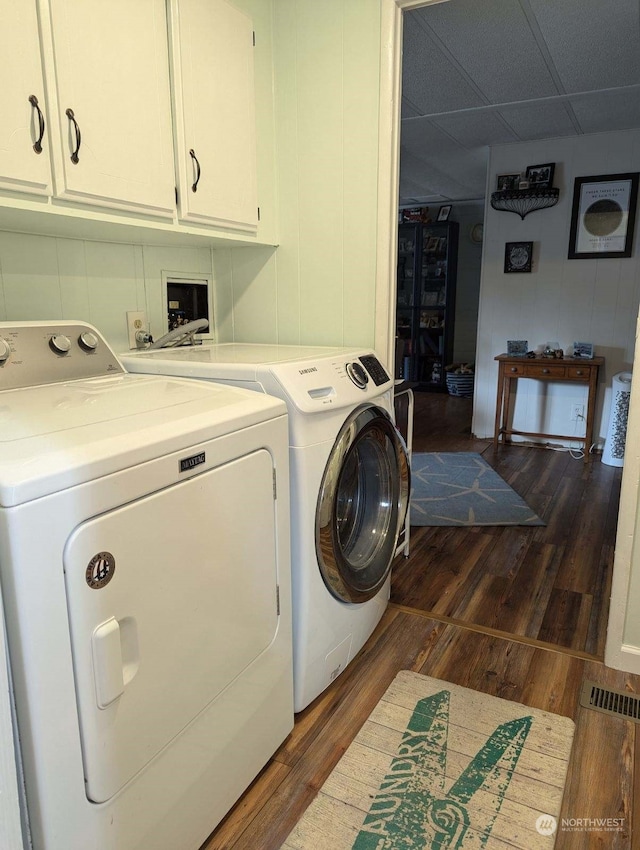 washroom featuring dark hardwood / wood-style flooring, cabinets, and washer and dryer