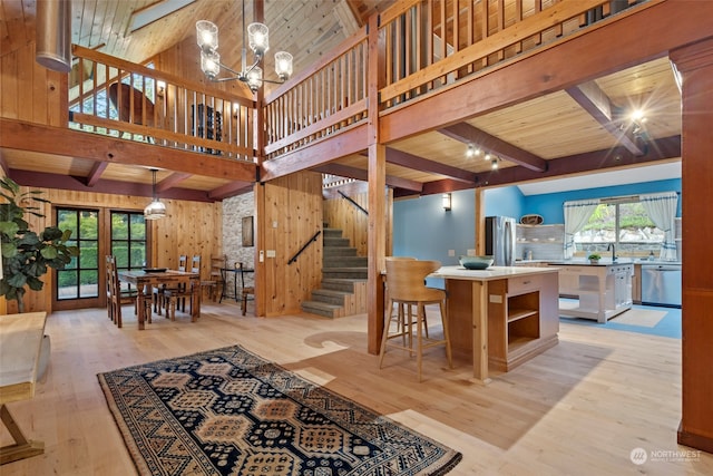 dining room featuring an inviting chandelier, wood ceiling, a towering ceiling, and light hardwood / wood-style floors