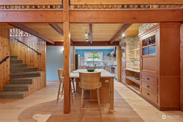 dining area with beam ceiling, light hardwood / wood-style floors, and wooden ceiling