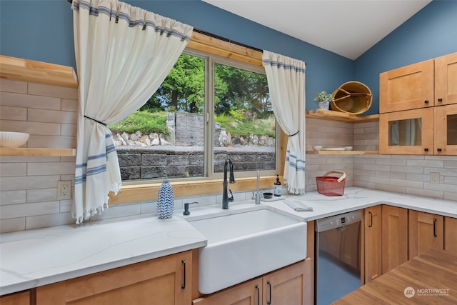 kitchen with lofted ceiling, sink, light stone countertops, decorative backsplash, and stainless steel dishwasher