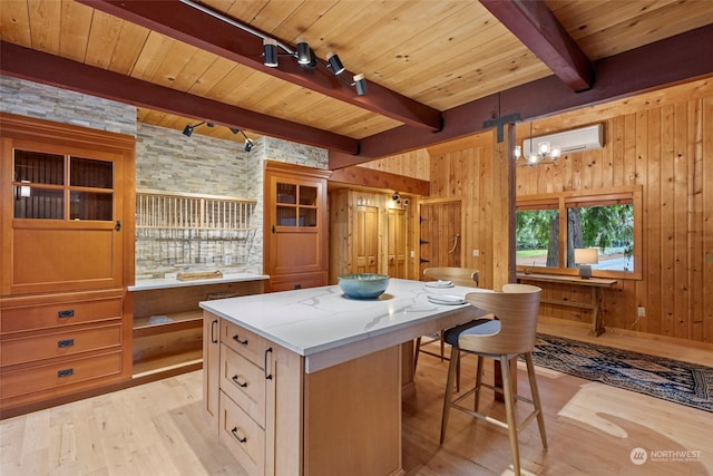 kitchen with a kitchen island, track lighting, light hardwood / wood-style floors, and wood walls