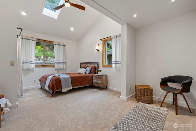 carpeted bedroom with a skylight, high vaulted ceiling, and ceiling fan