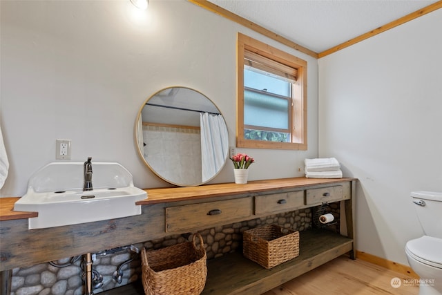 bathroom with sink, hardwood / wood-style flooring, ornamental molding, a shower with curtain, and toilet