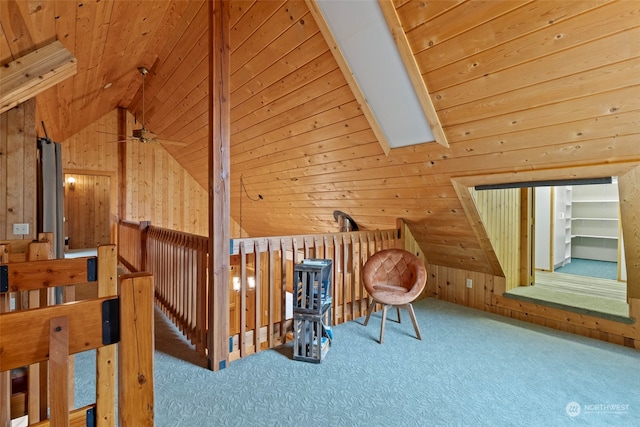 additional living space with vaulted ceiling with skylight, wooden walls, carpet floors, ceiling fan, and wooden ceiling