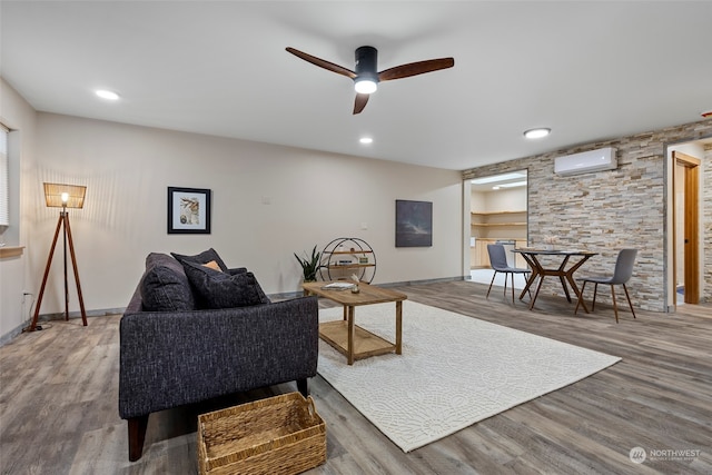 living room featuring hardwood / wood-style flooring, ceiling fan, and a wall unit AC