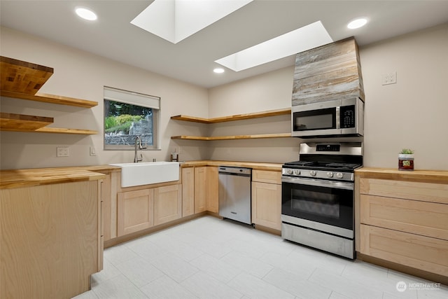 kitchen with sink, butcher block counters, a skylight, stainless steel appliances, and light brown cabinets