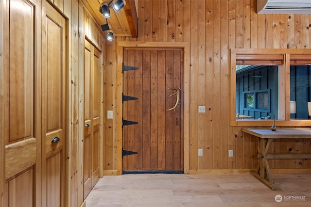 doorway with light hardwood / wood-style floors and wood walls