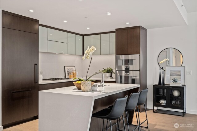 kitchen featuring sink, light hardwood / wood-style flooring, a kitchen island with sink, a breakfast bar area, and stainless steel appliances