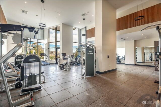 gym featuring a towering ceiling, tile patterned floors, and floor to ceiling windows