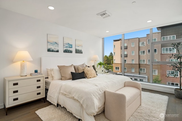 bedroom with floor to ceiling windows, multiple windows, and dark hardwood / wood-style floors