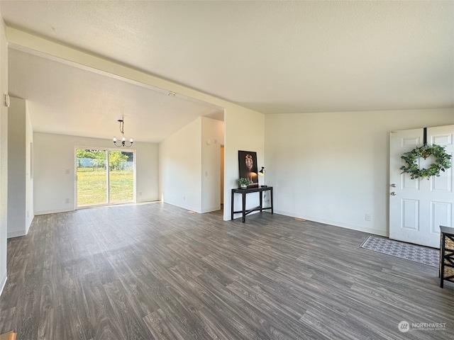 unfurnished living room featuring an inviting chandelier, dark wood-type flooring, and vaulted ceiling