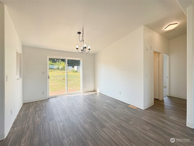 spare room featuring dark hardwood / wood-style flooring, a textured ceiling, and a chandelier