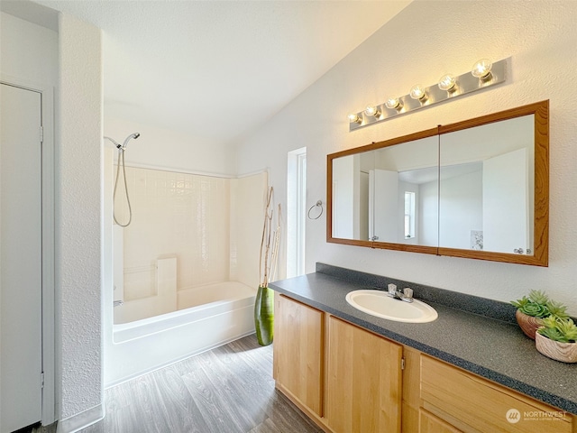 bathroom with lofted ceiling, shower / bathing tub combination, wood-type flooring, and vanity