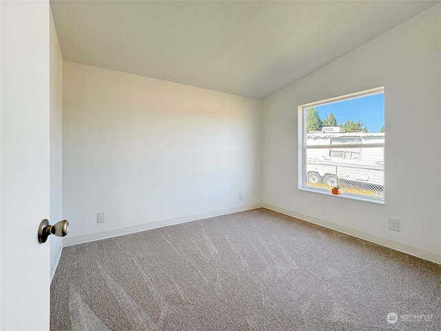 carpeted spare room featuring vaulted ceiling