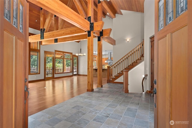 unfurnished living room with high vaulted ceiling, beamed ceiling, wood ceiling, and baseboards